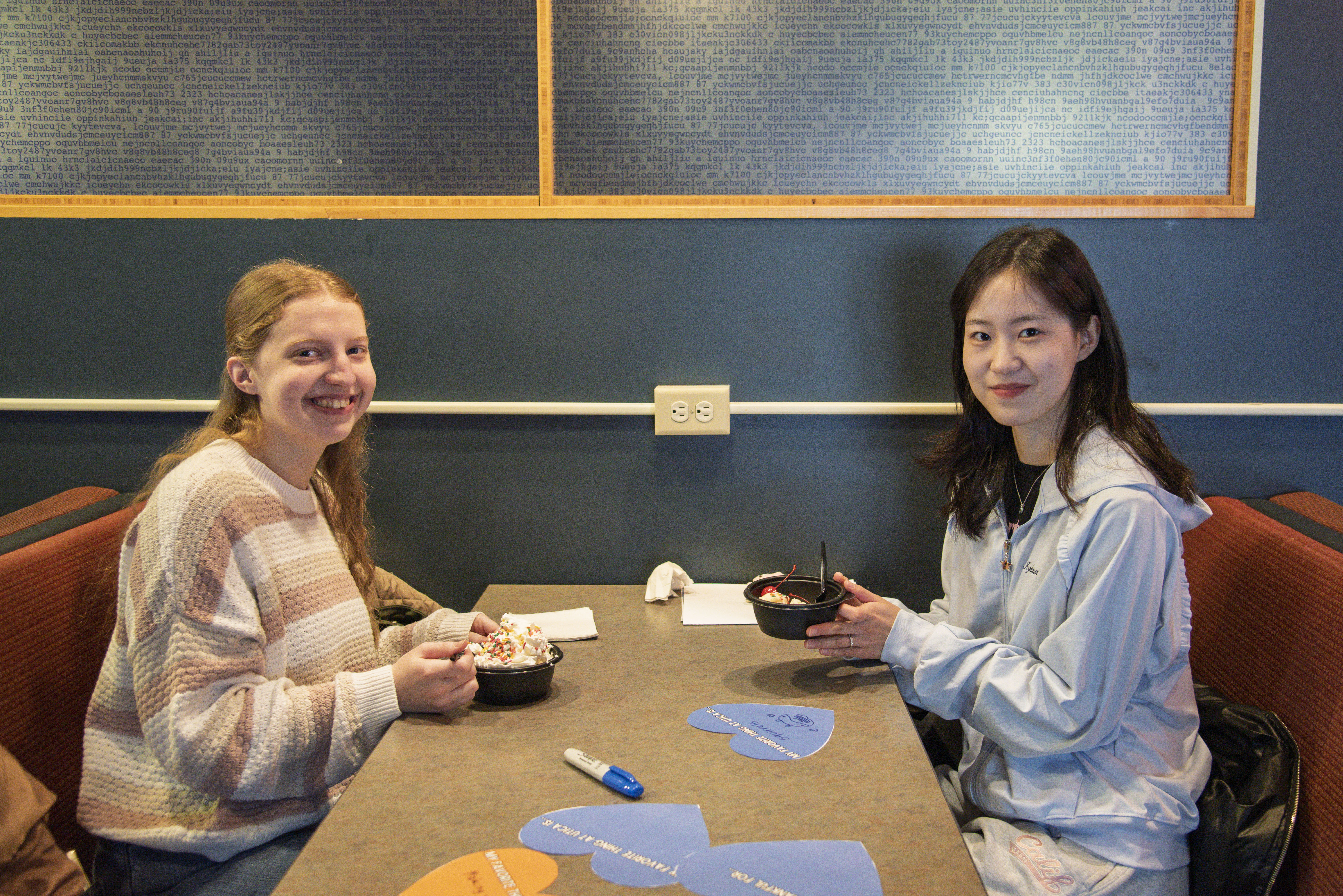 Two students sit in a booth at Pioneer Cafe and enjoy ice cream sundaes.