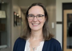 Nicole Scienza, in glasses and a blue sweater, smiles at the camera.
