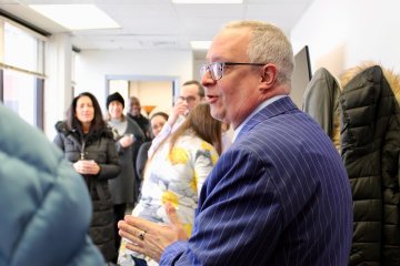 President Todd Pfannestiel, in blue striped suit, sands with crowd at the January 17, 2024 opening of the Center for Faculty Excellence.