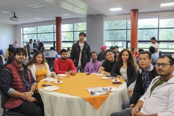 Students sit around a table at the International Welcome Reception at Utica University in 2024.