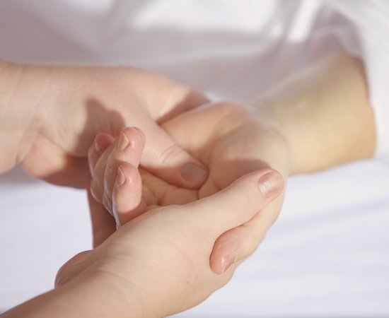 Hands massaging the palm of another hand.