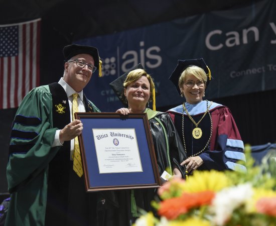 Professor of Occupational Therapy Mary Siniscaro stands between Provost Todd Pfannestiel and President Laura Casamento, holding her award at the 2023 Undergraduate Commencement Ceremony.