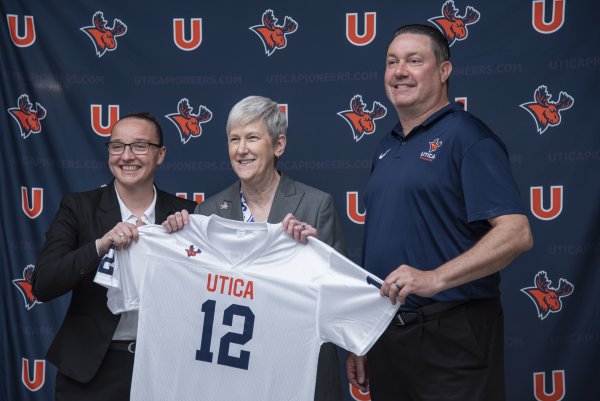 Kristin St. Hilaire, Stephanie Nesbitt, and Damian Boehlert hold up a Utica Pioneers jersey.