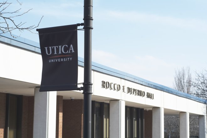 A blue Utica University banner hangs outside Rocco DePerno Hall.