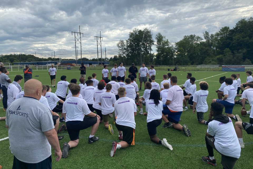 Participants kneel on the football field.