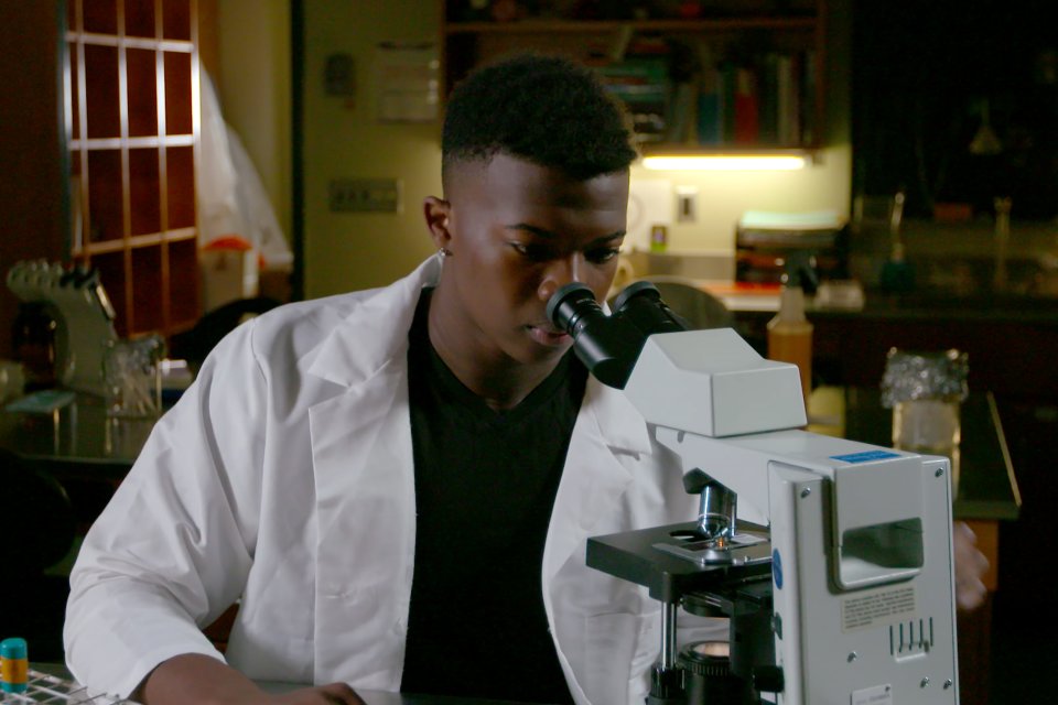 Dr Ivan Iton '21 looks through microscope