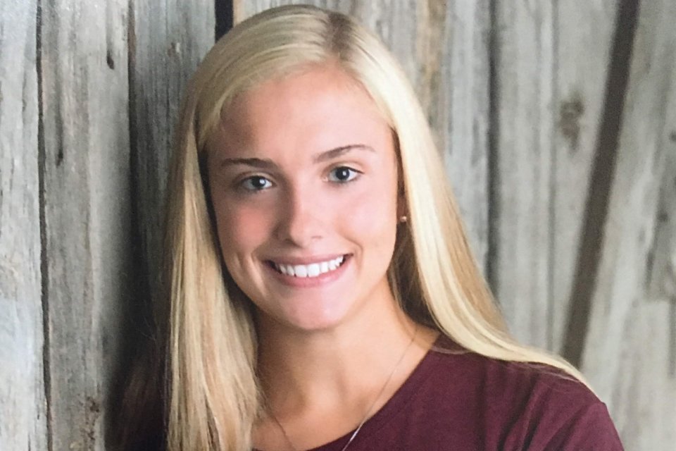 Isabelle LaBelle '23, stands in front of a wooden door, smiling.