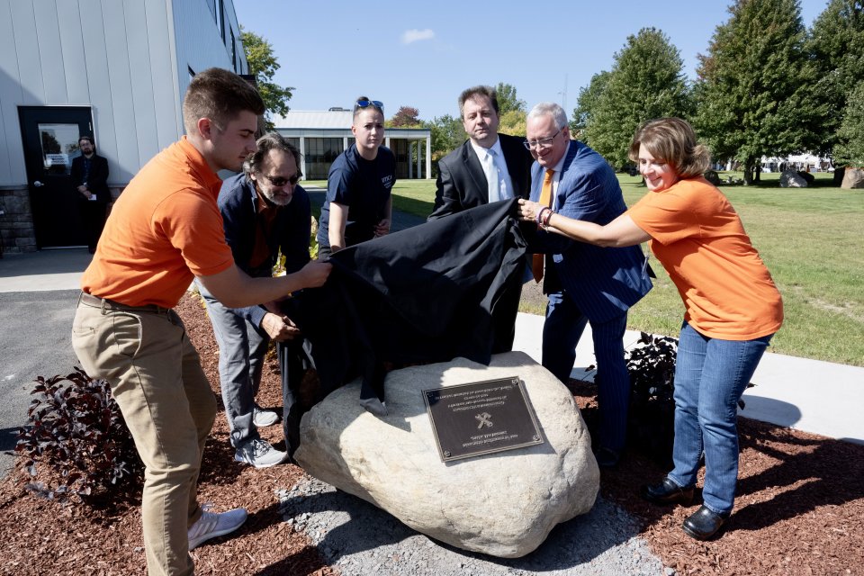 A plaque dedicating the campus pergola in honor of JP Ramel is unveiled.