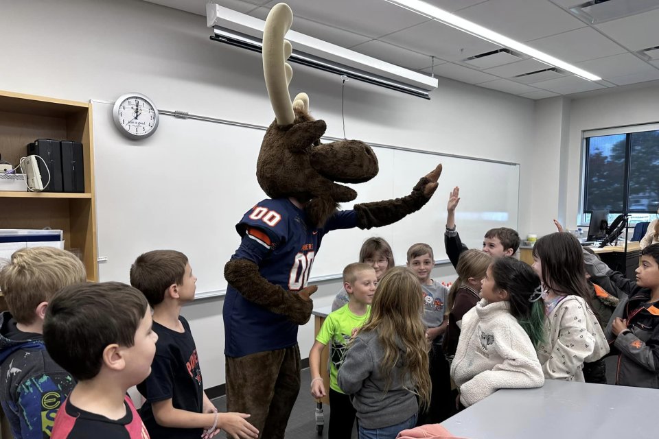 Trax the Moose high fives with elementary students from Little Falls.